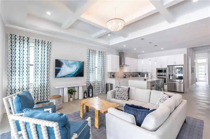Living area with coffered ceiling, beam ceiling, light wood-style floors, recessed lighting, and a chandelier