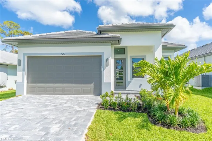 Prairie-style home featuring decorative driveway, stucco siding, a garage, and a front lawn
