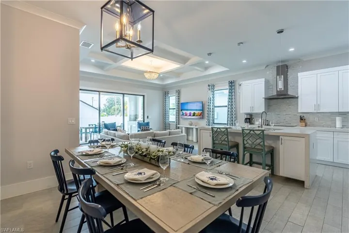 Dining area featuring coffered ceiling, healthy amount of natural light, beam ceiling, light wood-type flooring, and a chandelier