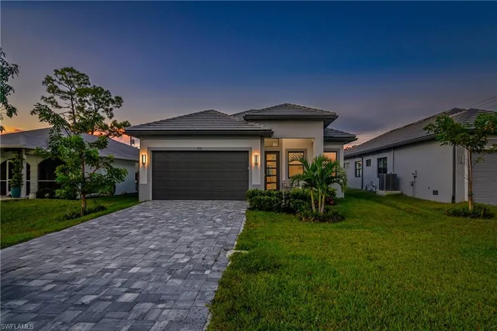Prairie-style house featuring a front lawn, decorative driveway, stucco siding, and a garage