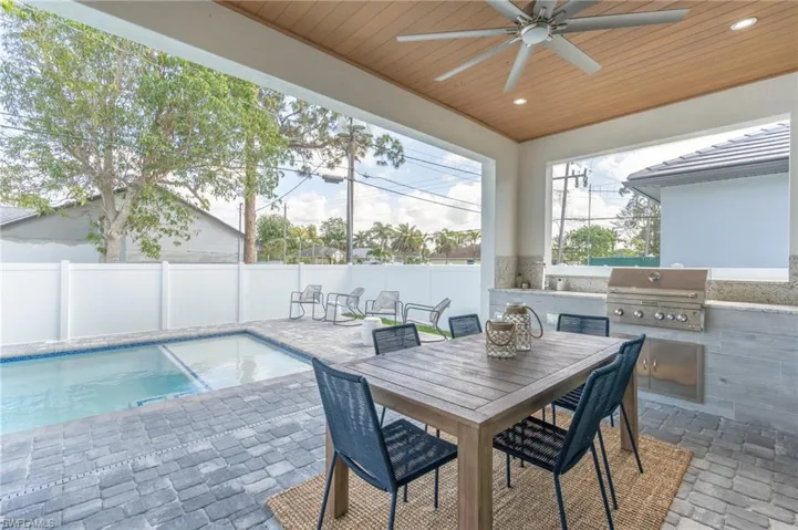 Fenced backyard featuring a patio area, an outdoor kitchen, ceiling fan, and outdoor dining area