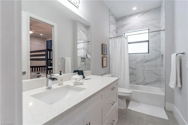 Bathroom with a combined bath / shower with marble appearance, vanity, recessed lighting, and a ceiling fan