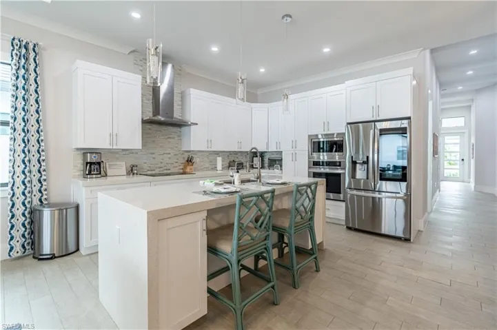 Kitchen with plenty of natural light, a kitchen breakfast bar, appliances with stainless steel finishes, white cabinetry, and recessed lighting