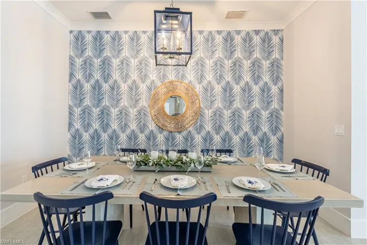 Dining space with light wood-type flooring, crown molding, and an accent wall