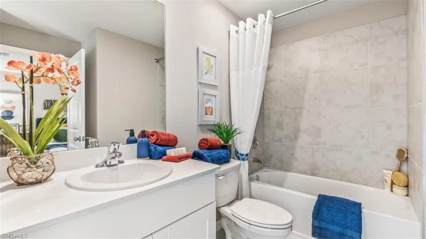 Full bathroom featuring toilet, vanity, and shower / bathtub combination with curtain