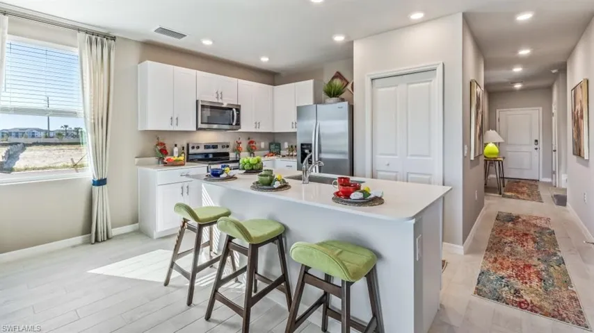 Kitchen with white cabinetry, sink, a breakfast bar area, stainless steel appliances, and a center island with sink