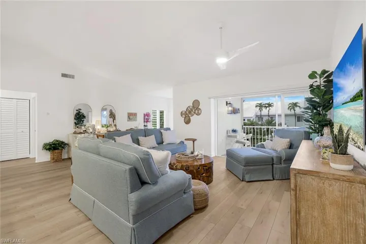 Living room with lofted ceiling, light vinyl plank flooring, and a ceiling fan