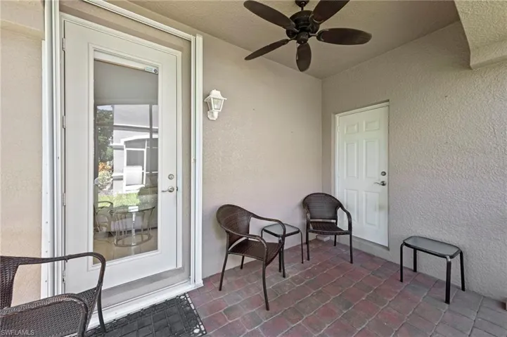 Doorway to property with a ceiling fan and stucco siding