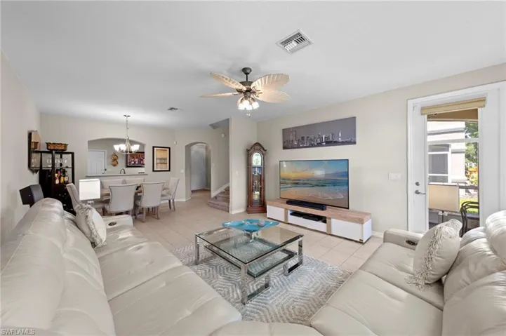 Living room featuring a chandelier, arched walkways, ceiling fan, and light tile patterned flooring