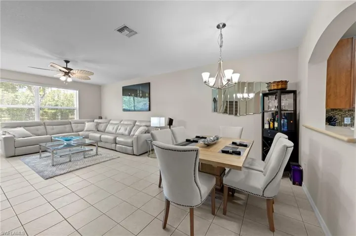 Dining area with light tile patterned floors, a chandelier, and ceiling fan