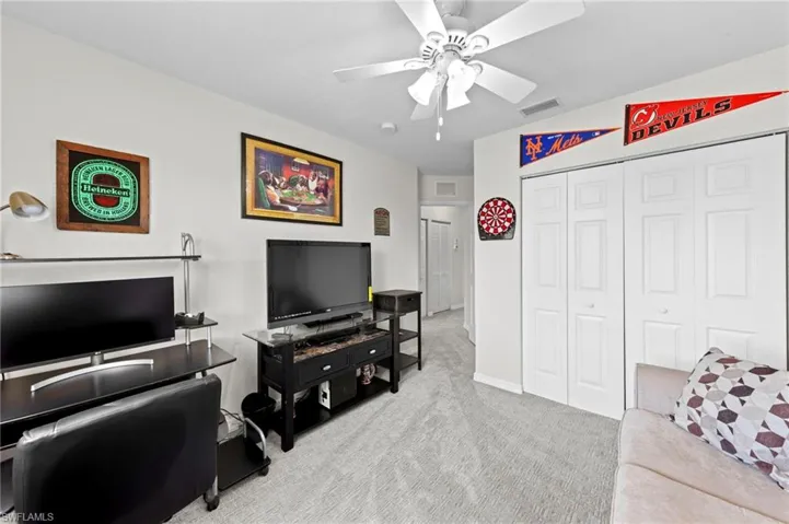 Carpeted living area with a ceiling fan and baseboards