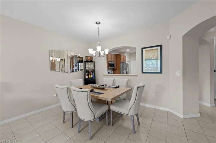 Dining room with arched walkways, a chandelier, and light tile patterned flooring