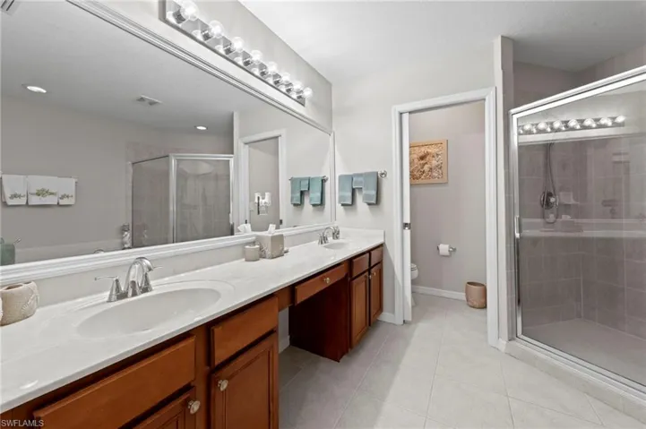 Full bathroom with double vanity, a stall shower, and tile patterned flooring