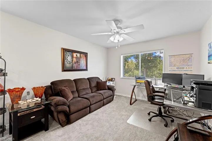Carpeted home office with baseboards and ceiling fan