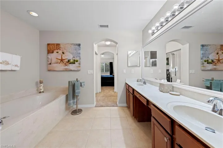 Ensuite bathroom with a bath, double vanity, tile patterned floors, and recessed lighting