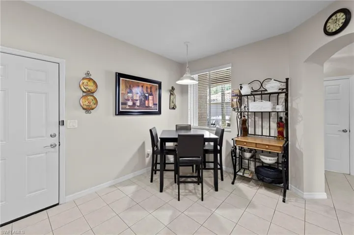 Dining area with arched walkways and light tile patterned flooring