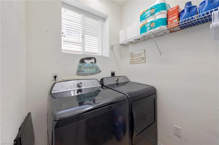 Laundry area featuring separate washer and dryer and a textured wall