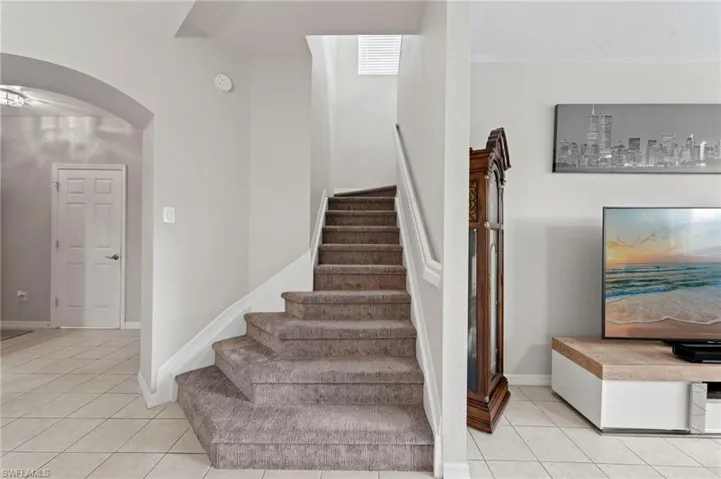 Stairs featuring arched walkways and tile patterned floors