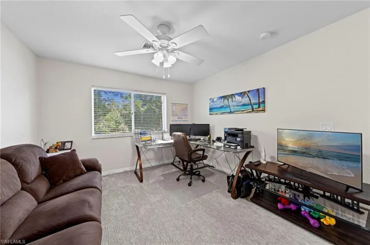 Carpeted office with a ceiling fan and baseboards