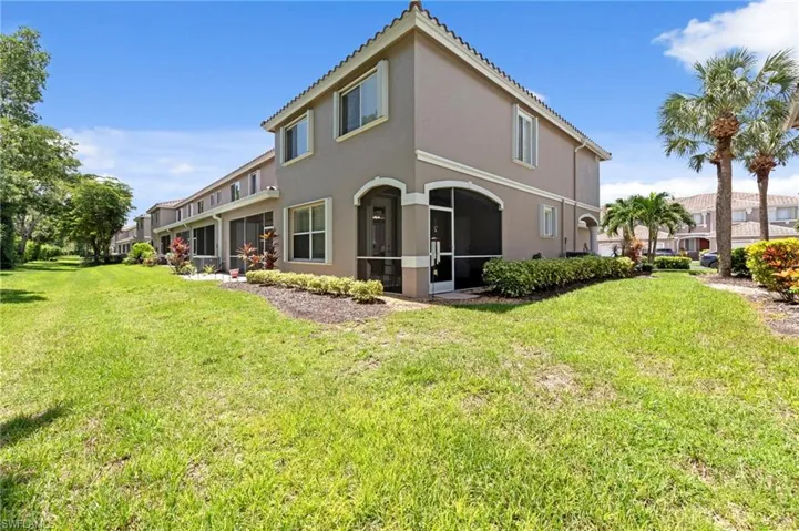 Rear view of property featuring stucco siding, a yard, and a tiled roof