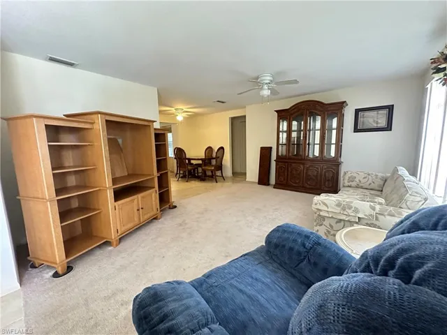 Carpeted living room with ceiling fan
