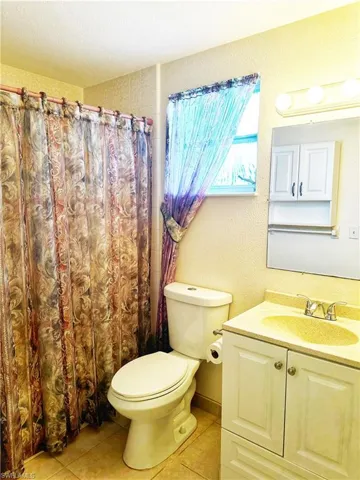 Primry bathroom with tile floors, toilet, tub/shower combo and vanity