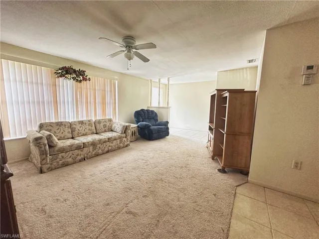 Living room with carpet, textured ceiling, and ceiling fan