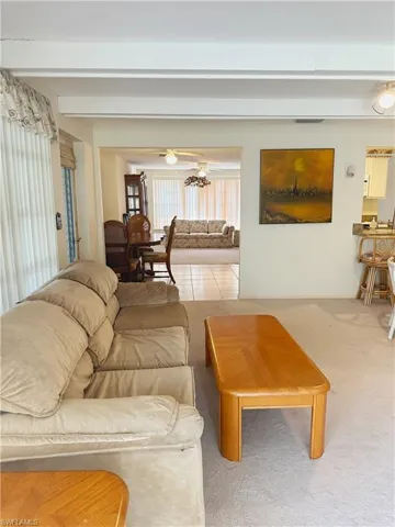 Carpeted great room featuring ceiling fan and beam ceiling