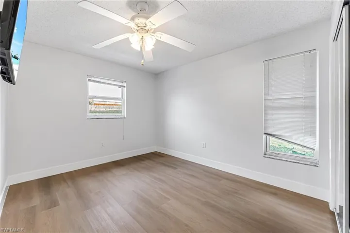 Spare room with ceiling fan, a healthy amount of sunlight, and hardwood / wood-style floors