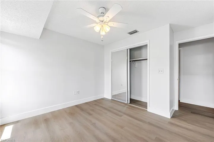 Unfurnished bedroom with a closet, ceiling fan, light hardwood / wood-style floors, and a textured ceiling