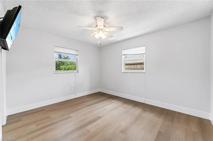 Empty room featuring ceiling fan, light hardwood / wood-style floors, and a textured ceiling