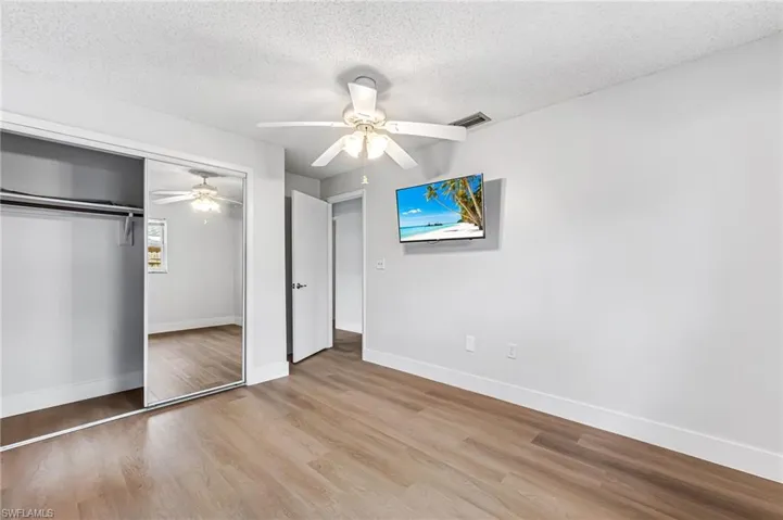Unfurnished bedroom with a textured ceiling, a closet, ceiling fan, and light wood-type flooring