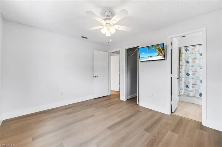 Unfurnished bedroom featuring ceiling fan, light hardwood / wood-style flooring, a textured ceiling, and connected bathroom