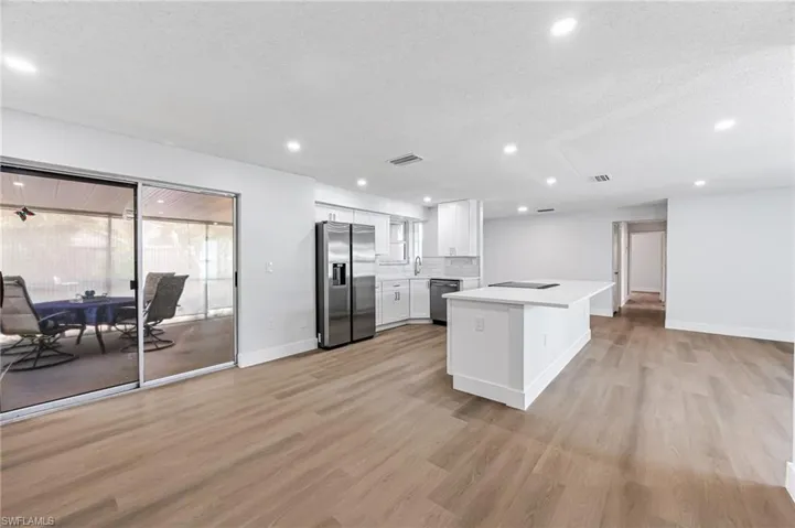 Kitchen featuring stainless steel appliances, tasteful backsplash, light wood-type flooring, white cabinets, and a textured ceiling