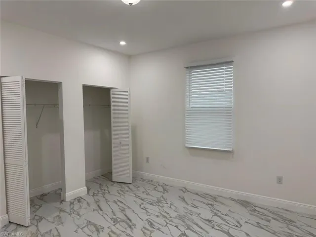 Unfurnished bedroom with multiple closets, light marble finish floors, recessed lighting, and baseboards