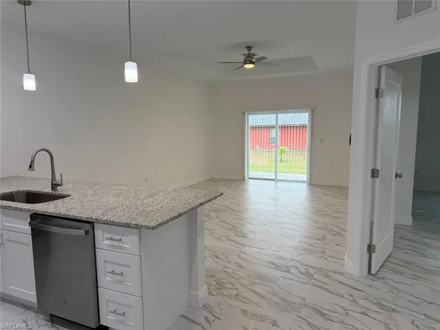 Kitchen with dishwasher, a sink, light marble finish floors, ceiling fan, and open floor plan