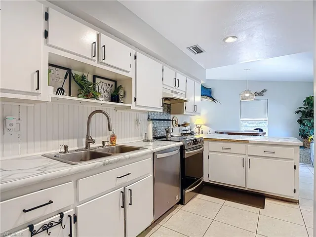 Kitchen with white cabinets, light countertops, a peninsula, and hanging light fixtures