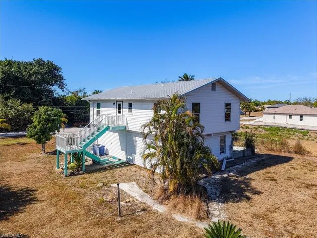 Back of house featuring a lawn and a metal roof