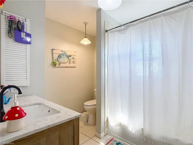 Bathroom with vanity, shower / tub combo, and light tile patterned floors