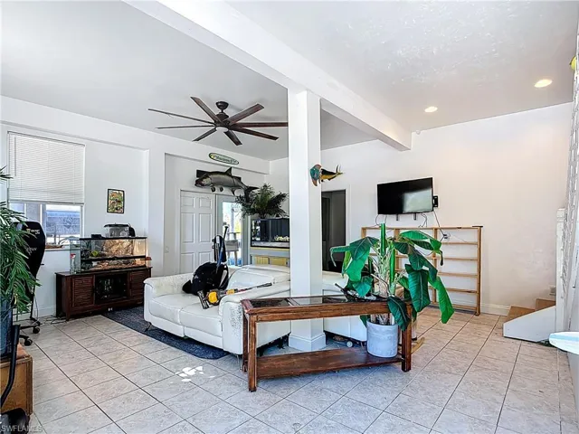 Living room with ceiling fan, light tile patterned floors, and recessed lighting