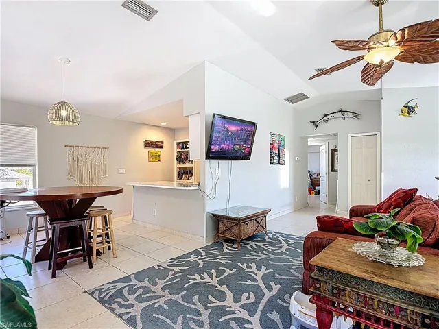Living room with vaulted ceiling, light tile patterned flooring, and ceiling fan