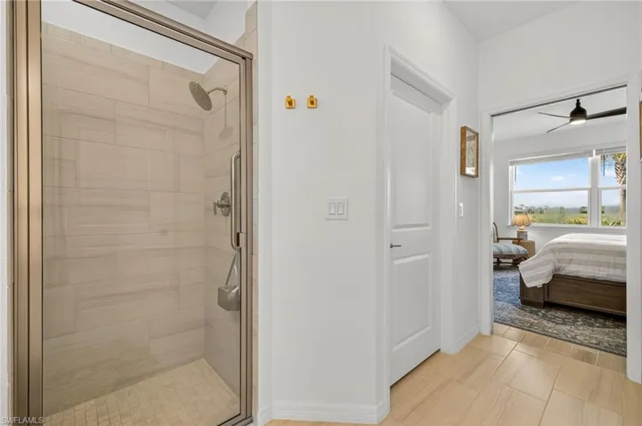Ensuite bathroom featuring a stall shower and ceiling fan