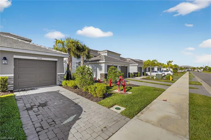 View of front of home featuring a residential view, stucco siding, decorative driveway, and stone siding