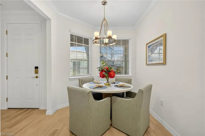 Dining space featuring crown molding, light wood-style flooring, and a chandelier