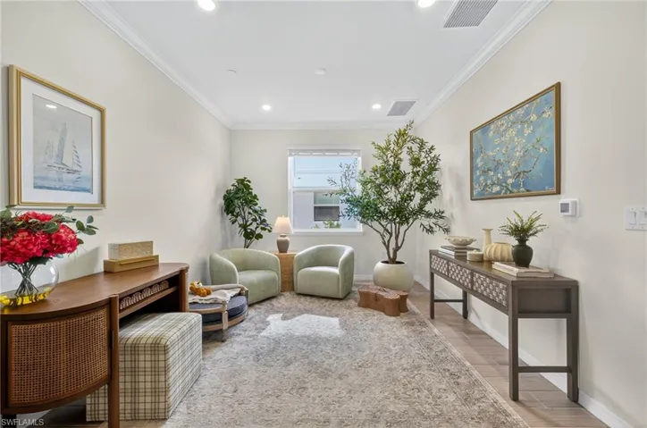 Living area featuring light wood-type flooring, crown molding, and recessed lighting