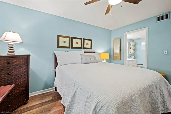 Bedroom featuring hardwood / wood-style flooring, ceiling fan, and ensuite bath