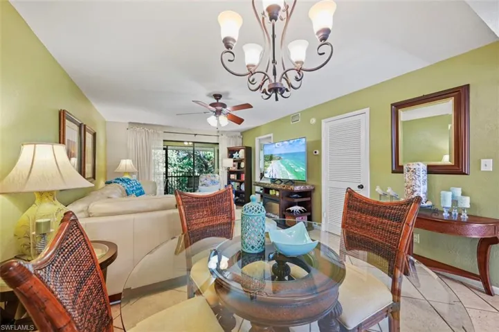 Tiled dining space with ceiling fan with notable chandelier