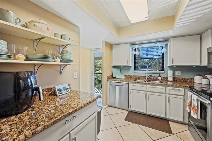 Kitchen featuring white cabinetry, sink, appliances with stainless steel finishes, and dark stone counters