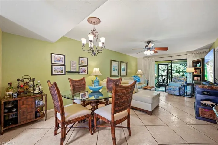Dining space featuring ceiling fan with notable chandelier and light tile patterned floors