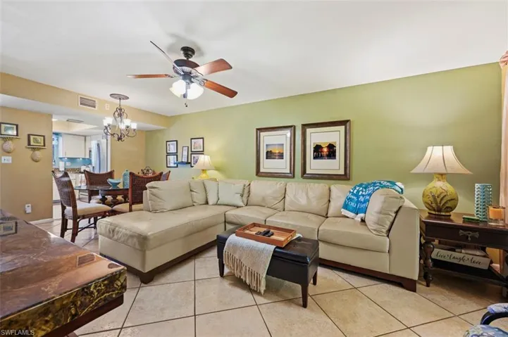 Tiled living room featuring ceiling fan with notable chandelier